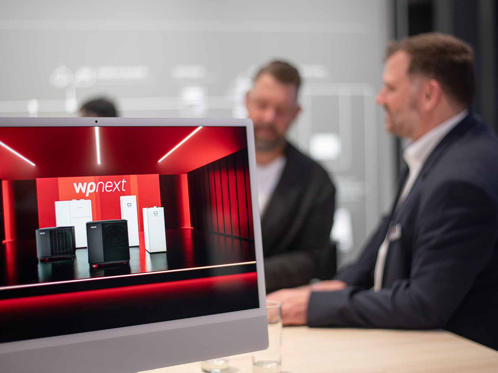 Bildschirm mit dem Visual von wpnext mit unscharfen Personen im Hintergrund