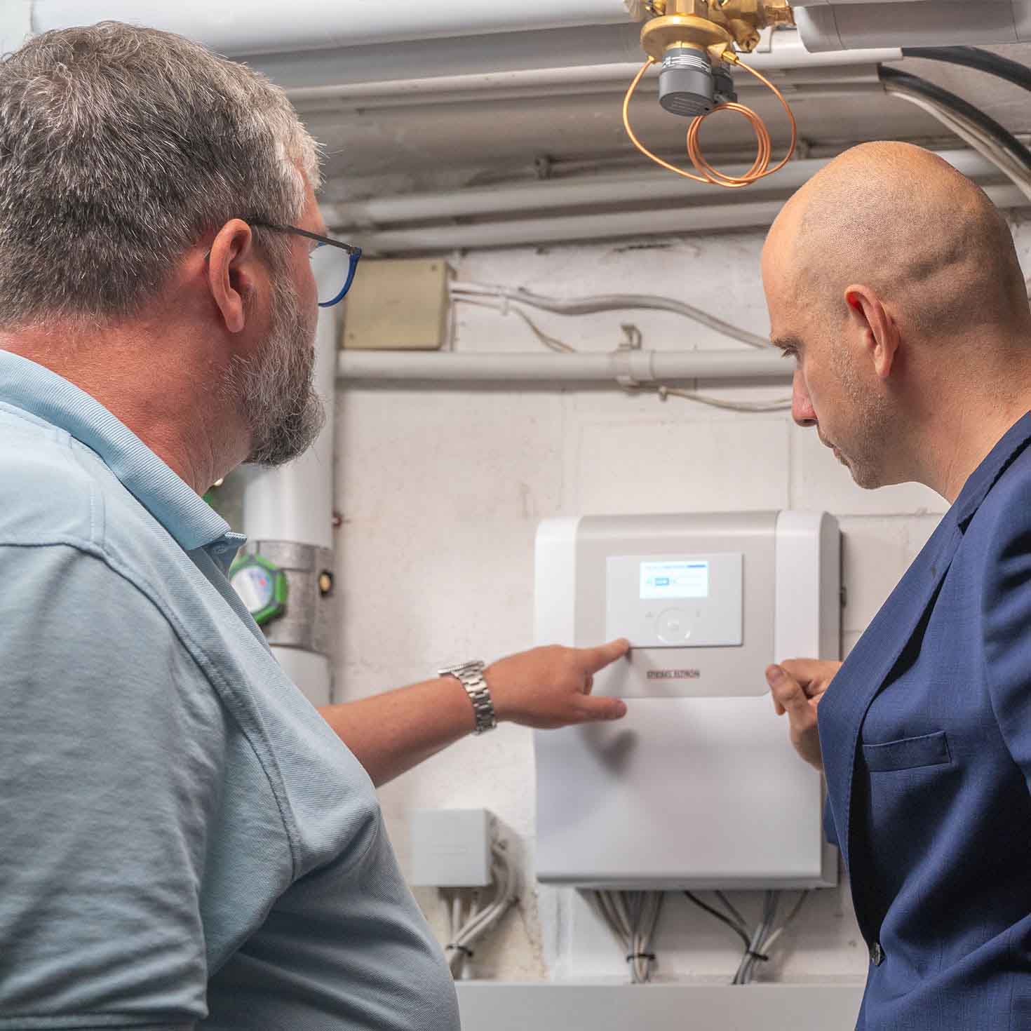 Zwei Männer an der Bedieneinheit einer Wärmepumpe