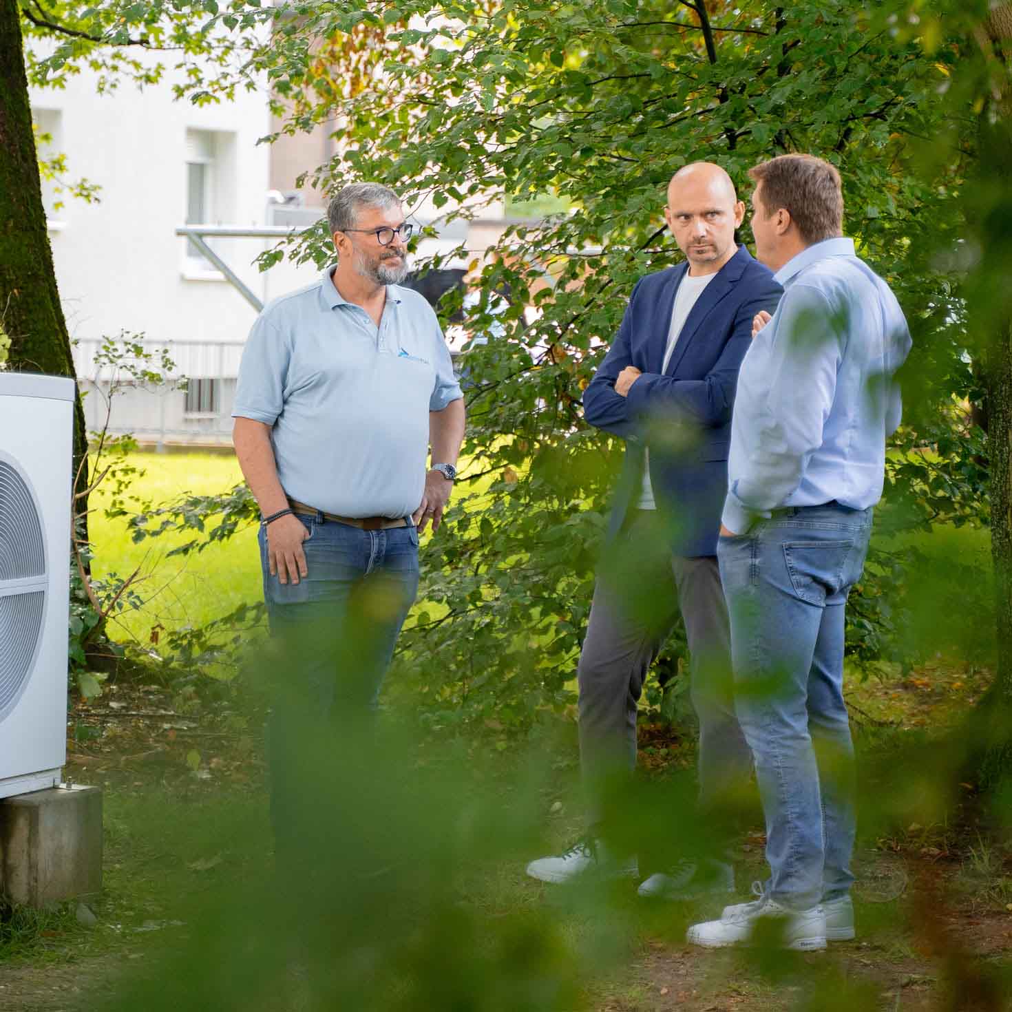 Drei Personen in einem Garten im Gespräch
