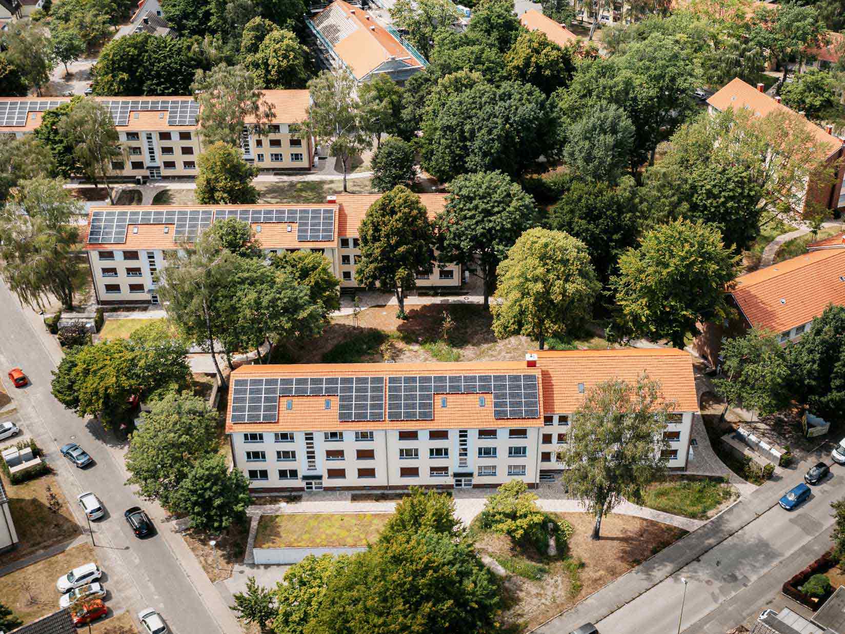 Quartier mit mehreren Mehrfamilienhäusern und Photovoltaik auf dem Dach aus der Vogelperspektive