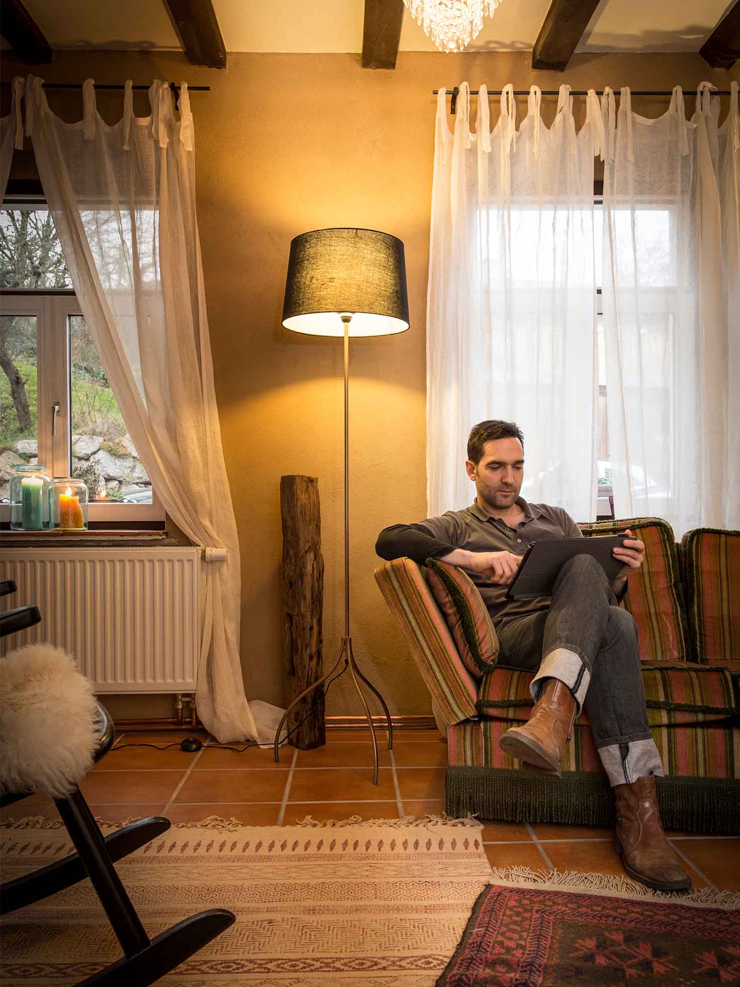 Mann sitzt auf einem Sofa und hält ein Tablet