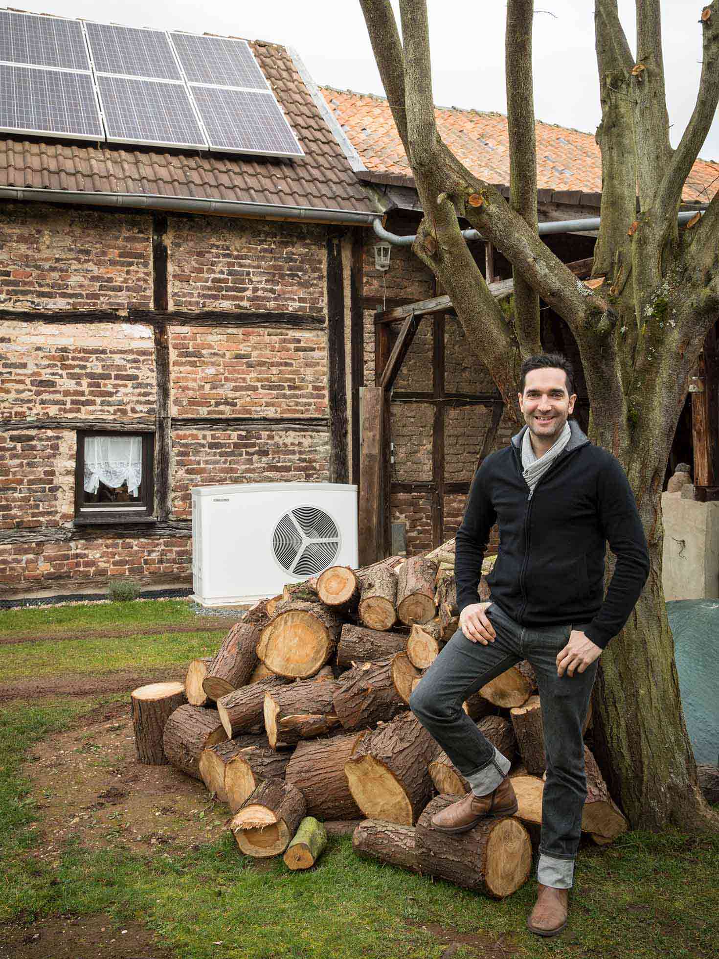 Mann steht vor einem Backsteinhaus mit STIEBEL ELTRON Wärmepumpe und Solaranlage