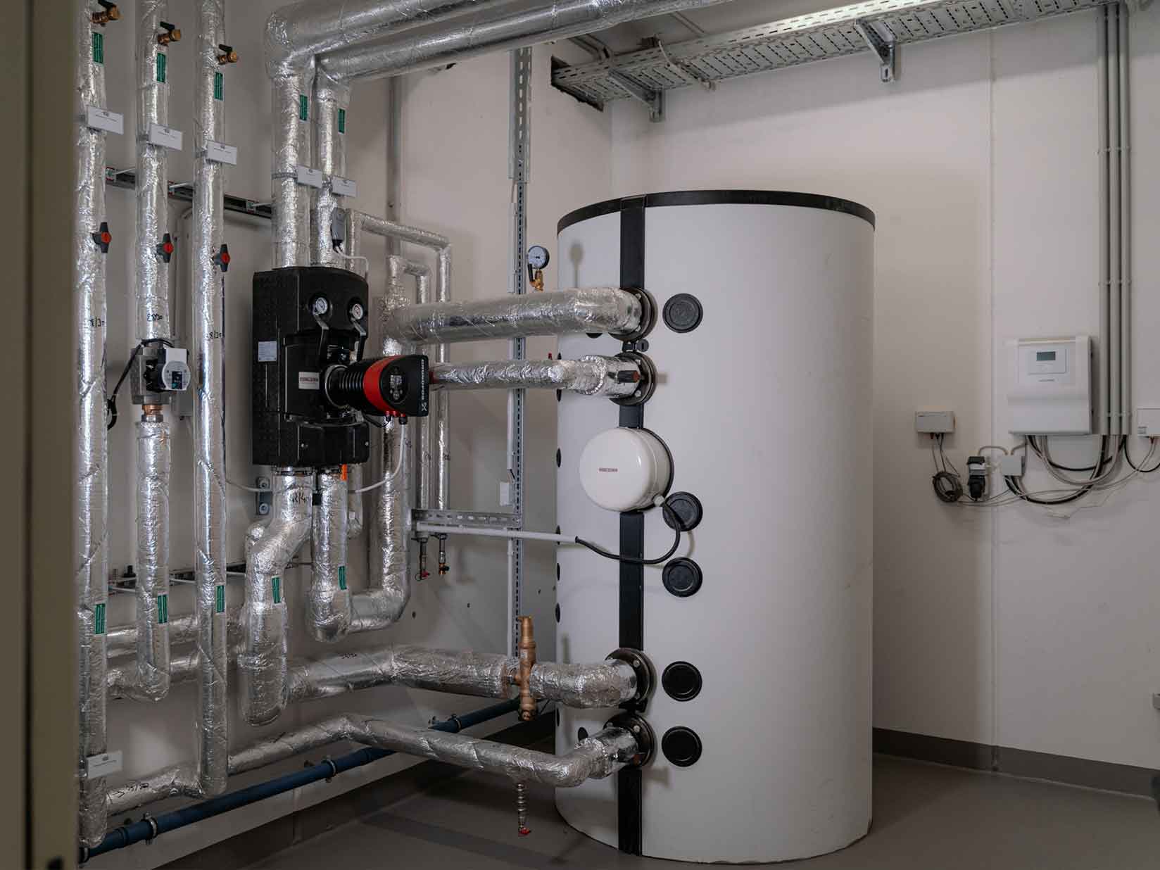 Warmwasserspeicher im Technikraum mit Rohrleitungen