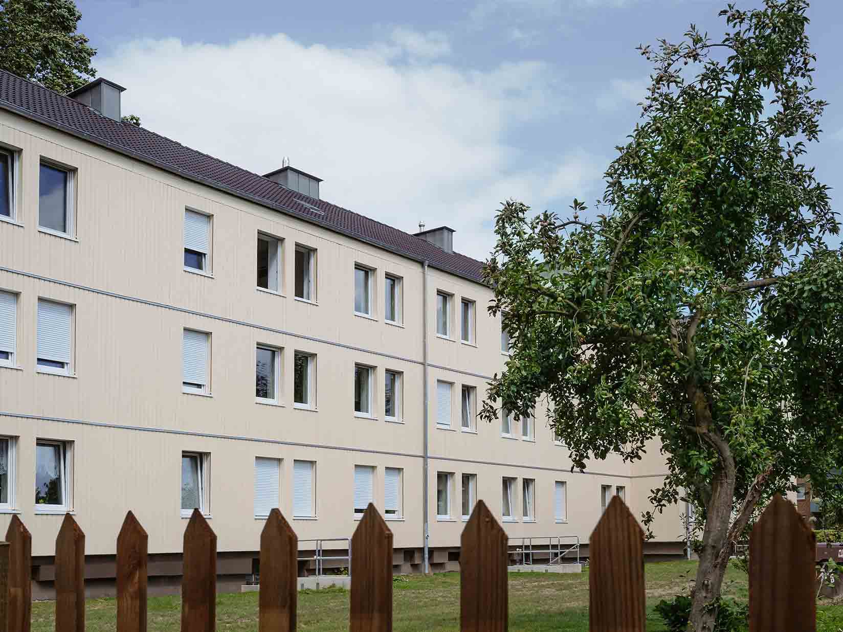Mehrfamilienhaus hinter einem Holzzaun