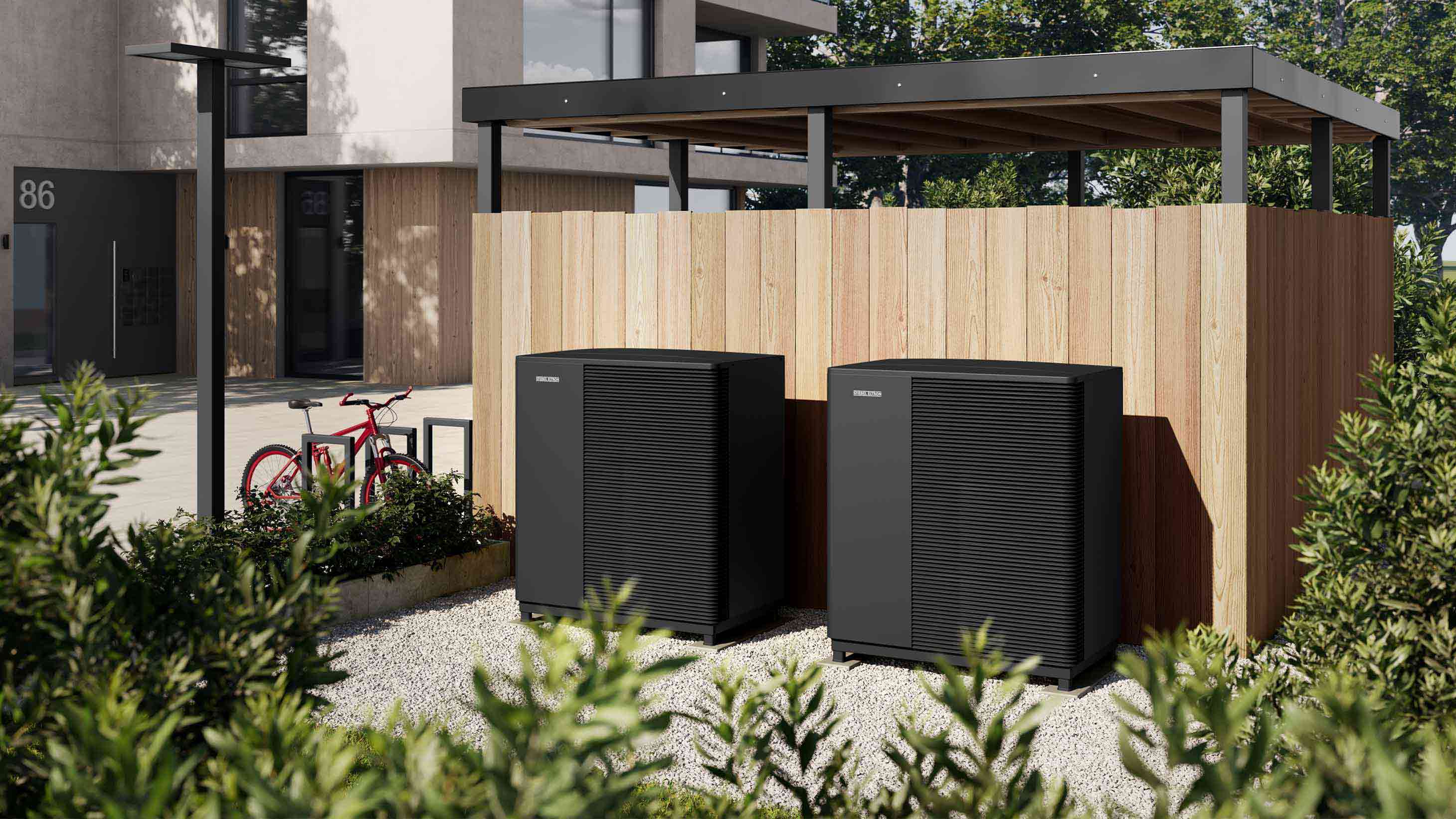 In einem begrünten, modern gestalteten Innenhof stehen zwei Wärmepumpen vor einem mit Holz verkleideten Unterstand.