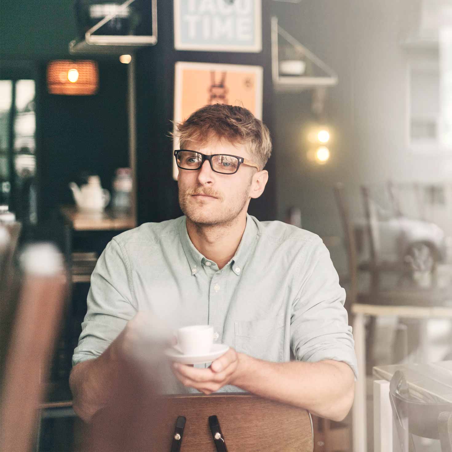 Mann sitzt in einem Café mit einer Tasse in den Händen