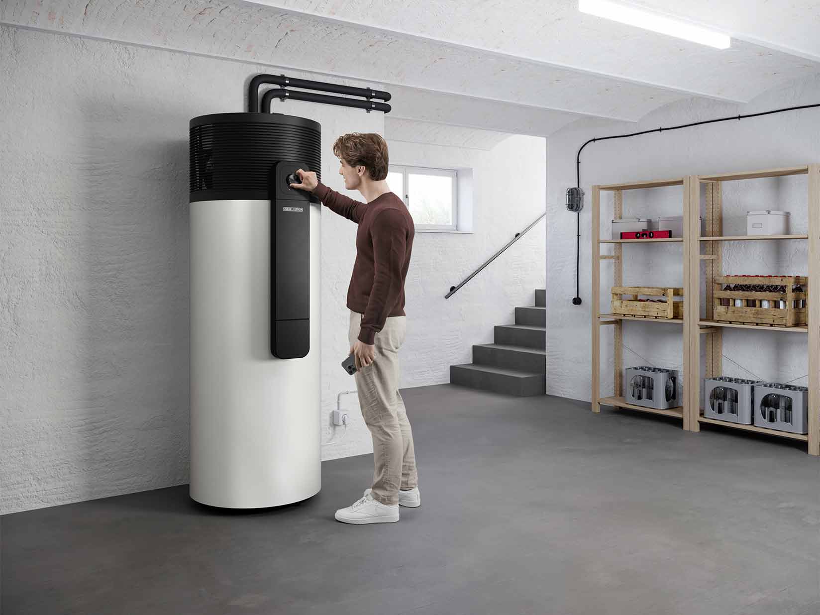 Ein Mann steht im Heizungskeller und bedient eine Warmwasser-Wärmepumpe