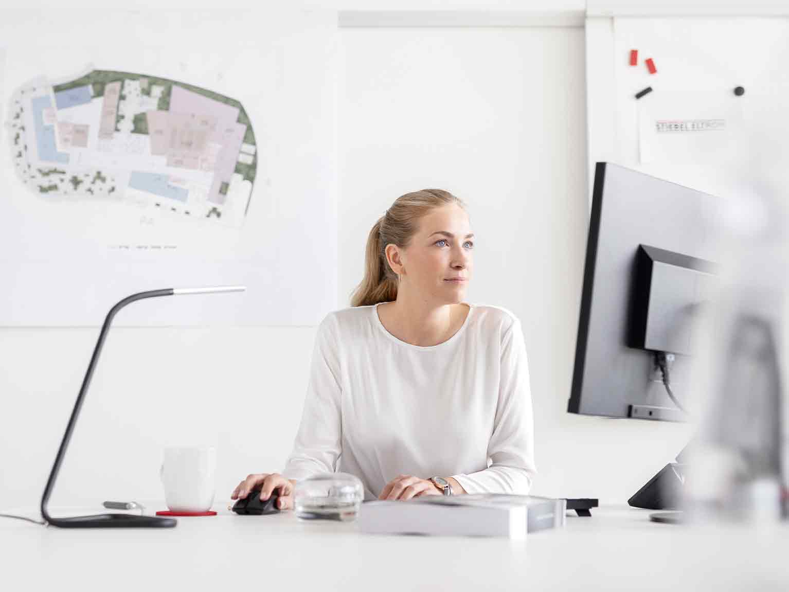 Frau sitzt am Schreibtisch und arbeitet am PC