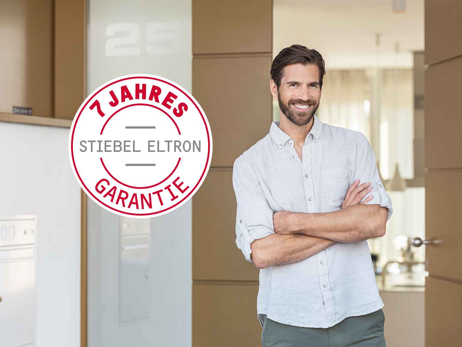 Mann lehnt mit verschränkten Armen am Hauseingang, auf dem Bild ist ein Signet mit der Aufschrift 7 JAHRE STIEBEL ELTRON GARANTIE