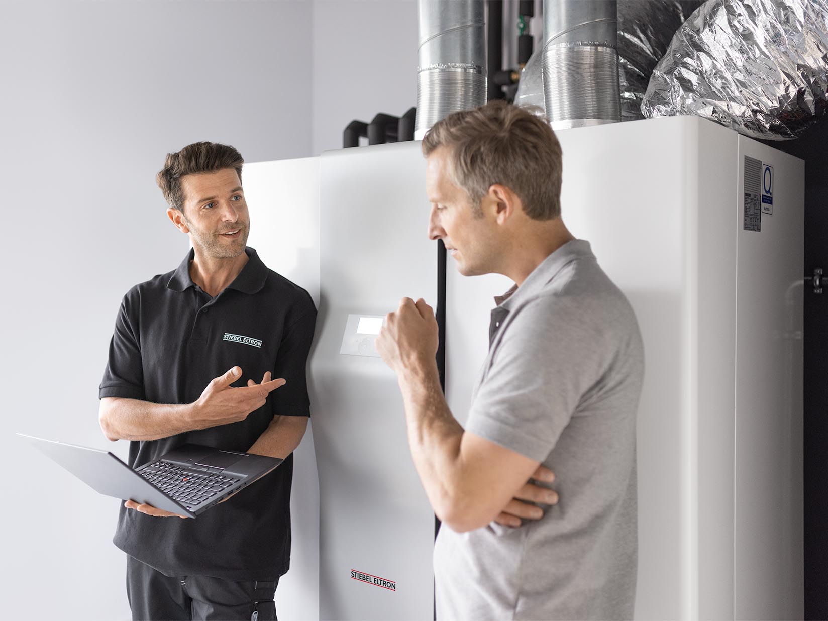 Handwerker und Kundendienstmitarbeiter vor einer Wärmepumpe
