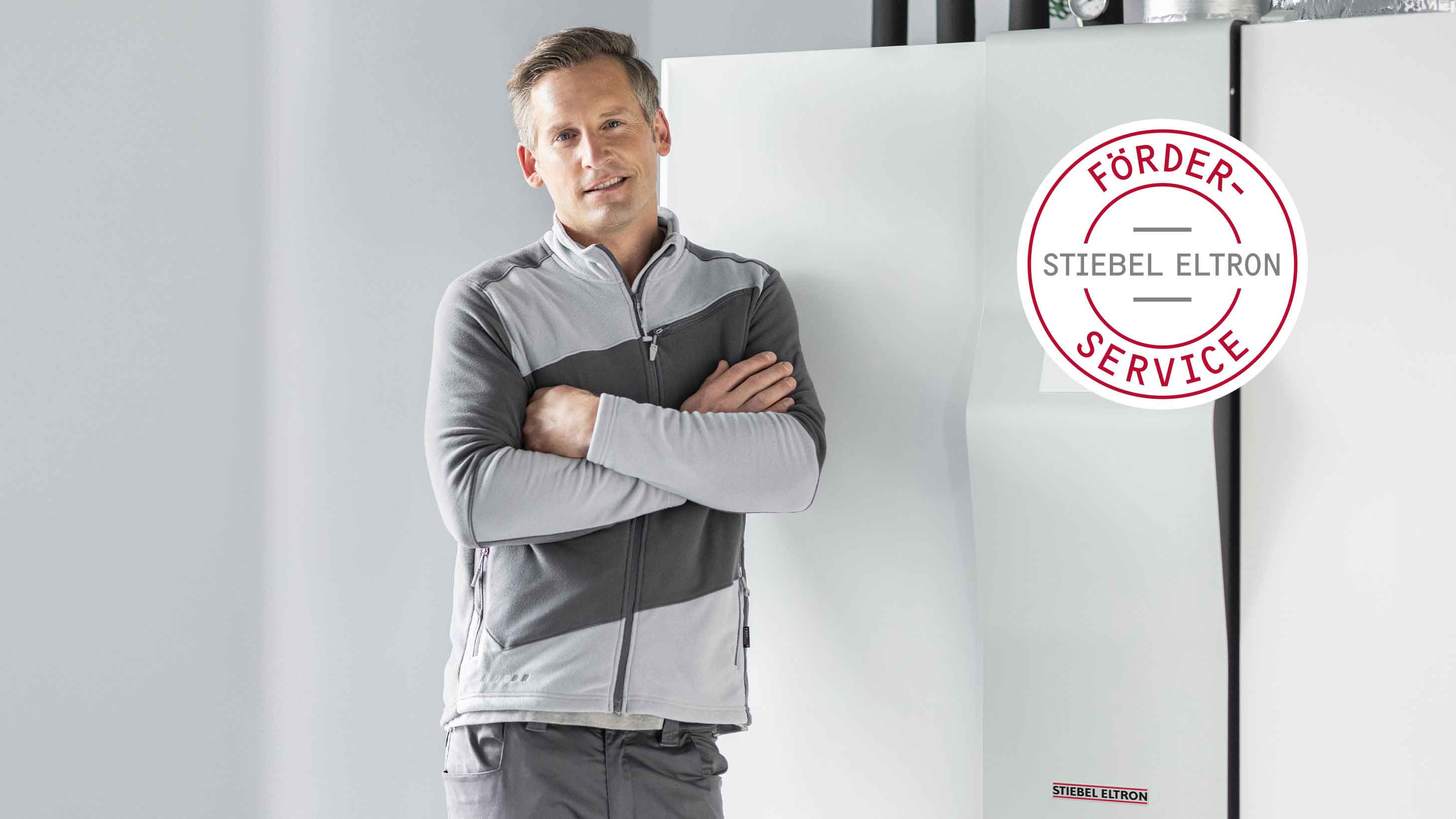Ein Handwerker lehnt an einer Wärmepumpe