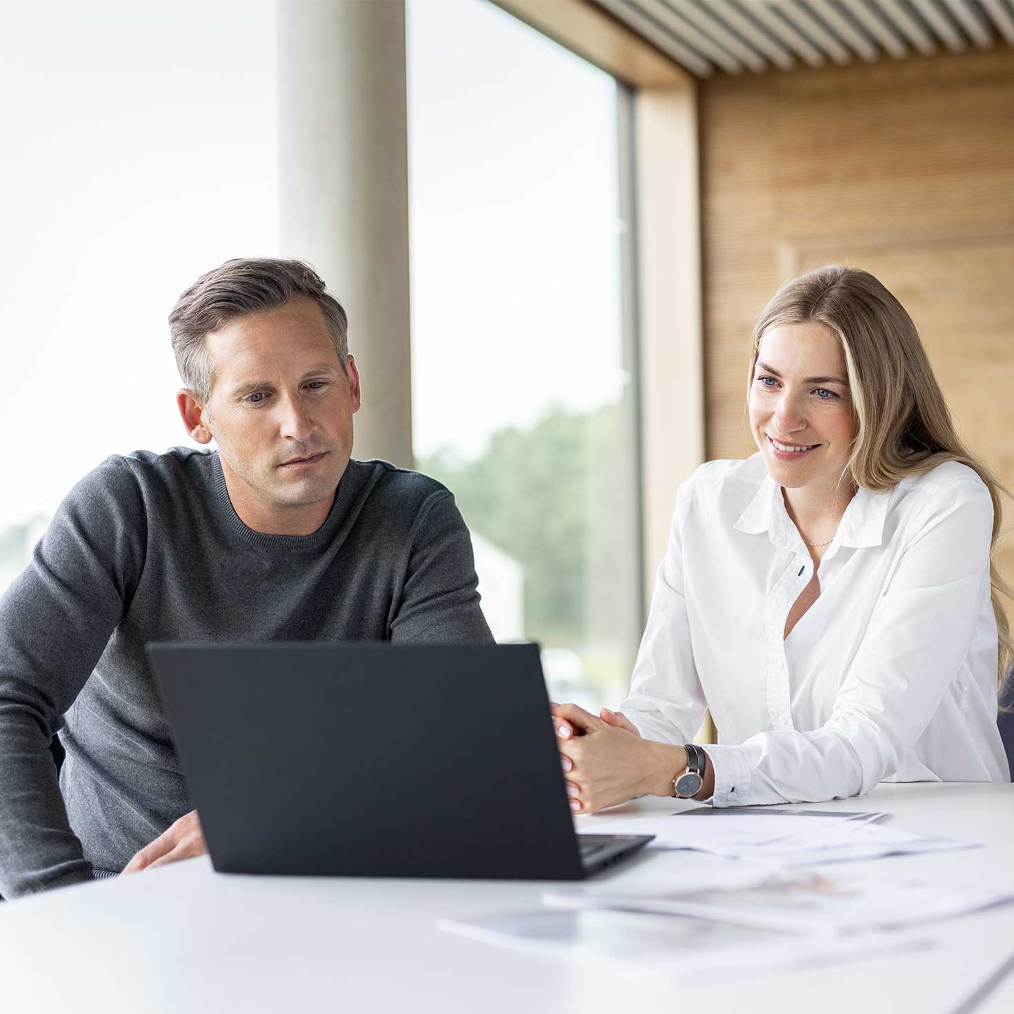 Ein Mann und eine Frau schauen gemeinsam auf den Bildschirm eines Laptops