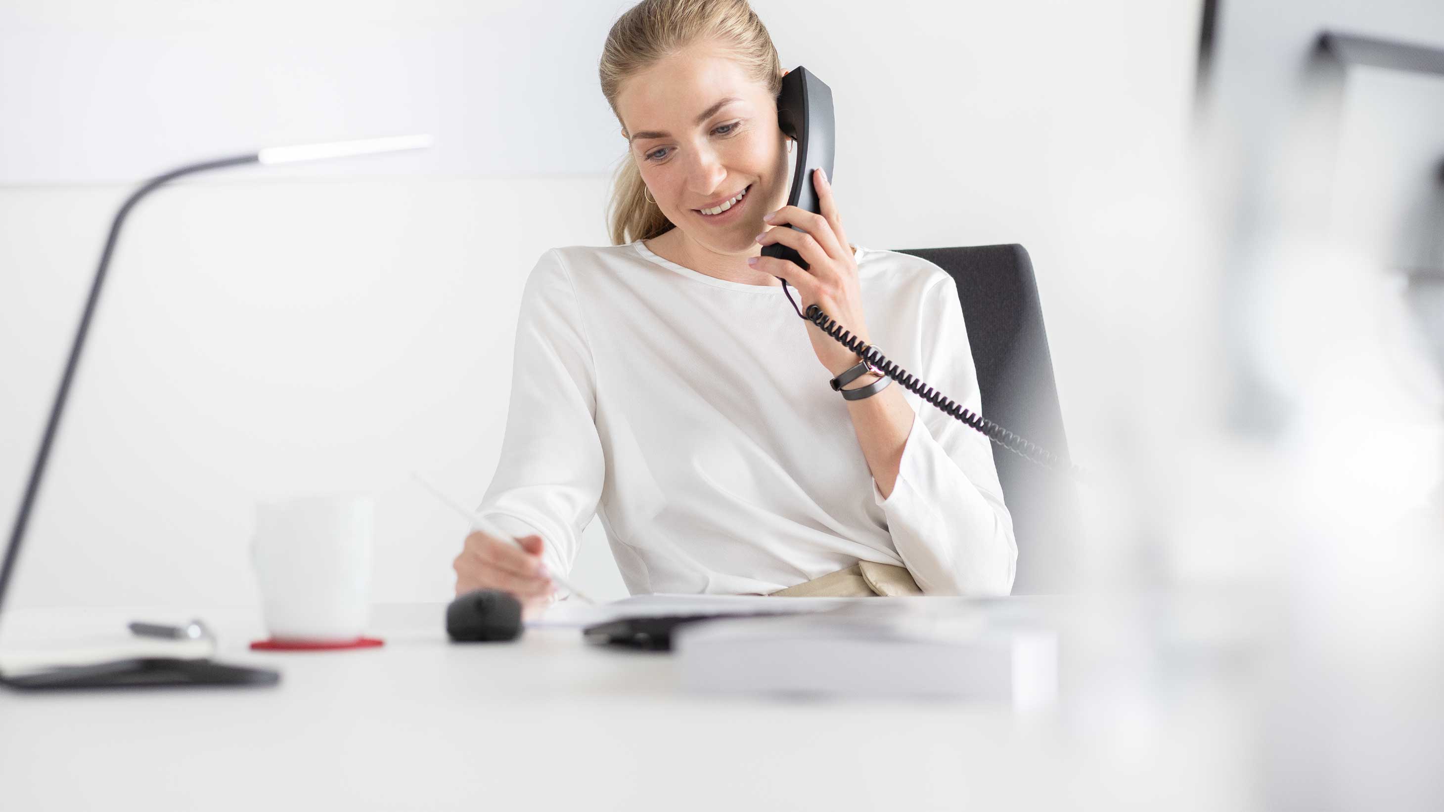 Eine Service-Mitarbeiterin telefoniert und macht sich Notizen