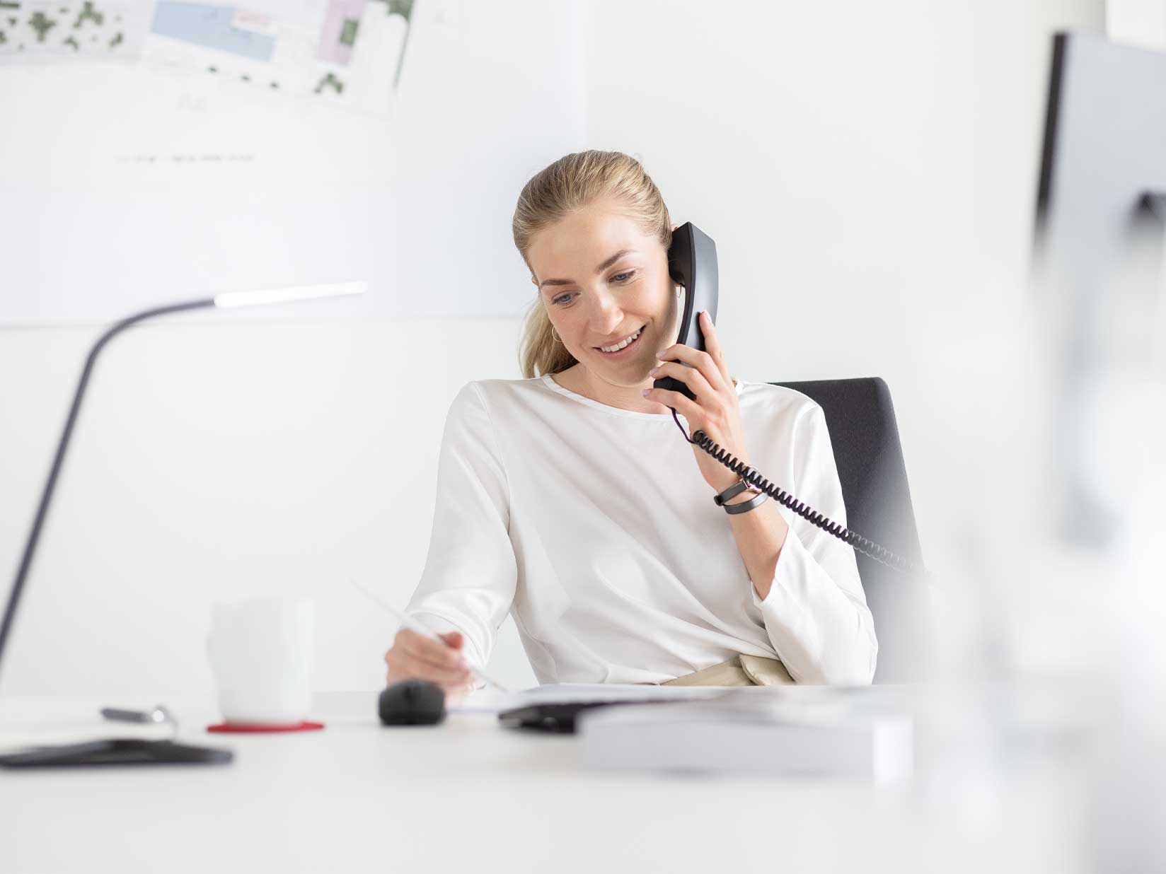 Eine Servicemitarbeiterin telefoniert und macht sich Notizen