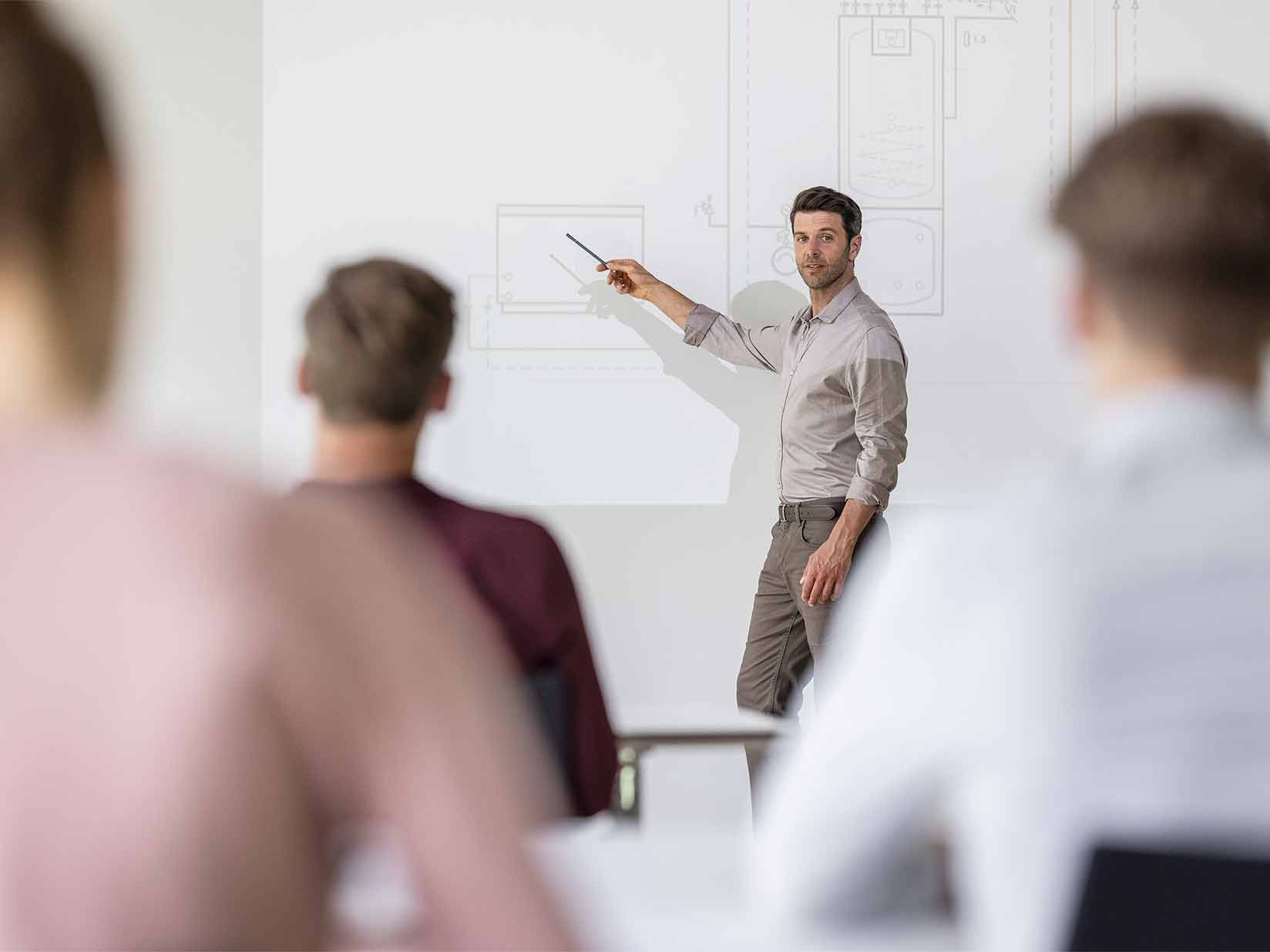 Ein STIEBEL ELTRON Trainer steht am digitalen Schulungsboard und erklärt ein Hydraulikschaltplan einer Wärmepumpe