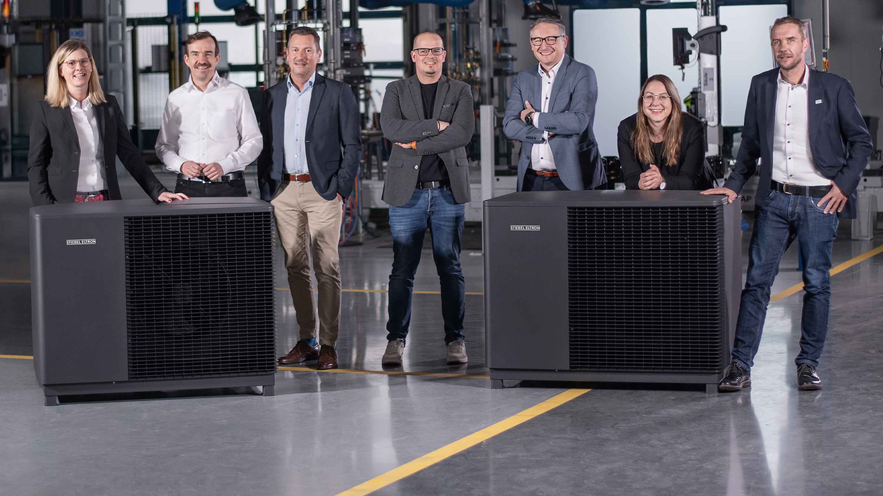 Vertriebmitarbeiter von STIEBEL ELTRON und Fachhandwerker unterhalten sich vor der Wärmepumpe