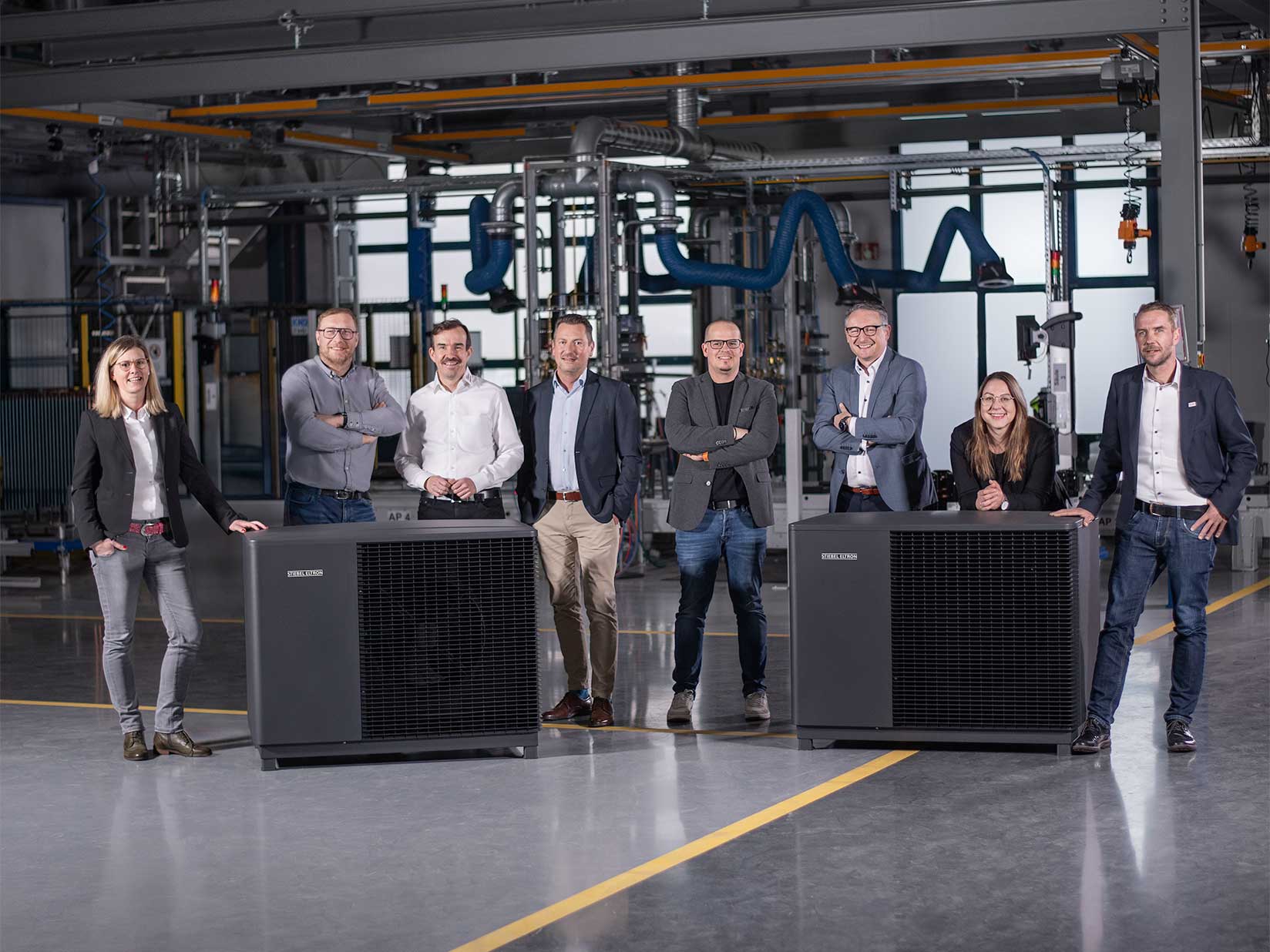 STIEBEL ELTRON-Mitarbeiter stehen neben den Wärmepumpen der WPL-A-Serie in einer Fertigungshalle