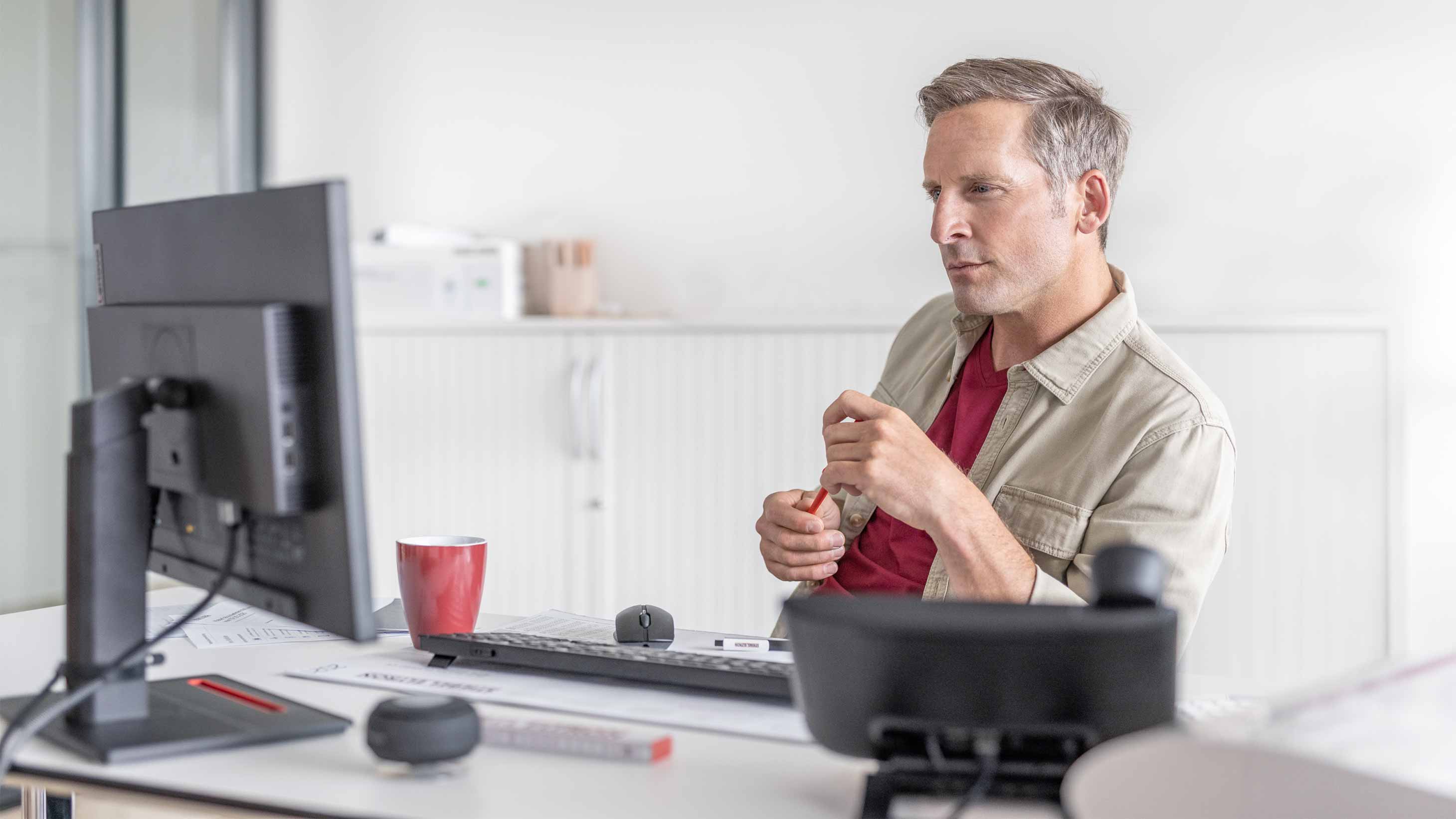 Handwerker am Schreibtisch vor einem Computermonitor