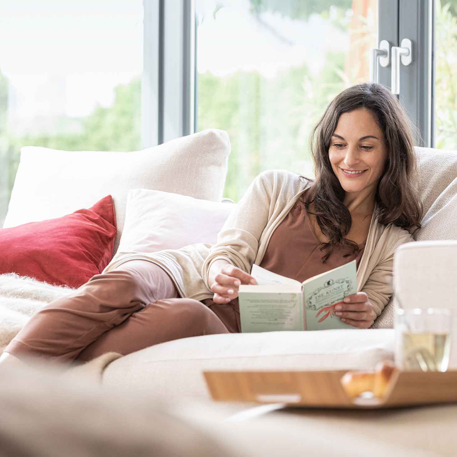 Eine Frau sitzt auf einem Sofa und liest ein Buch