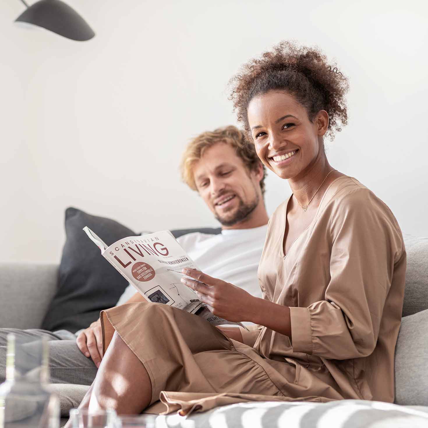 Ein Paar sitzt auf einer Couch und liest in einem Magazin