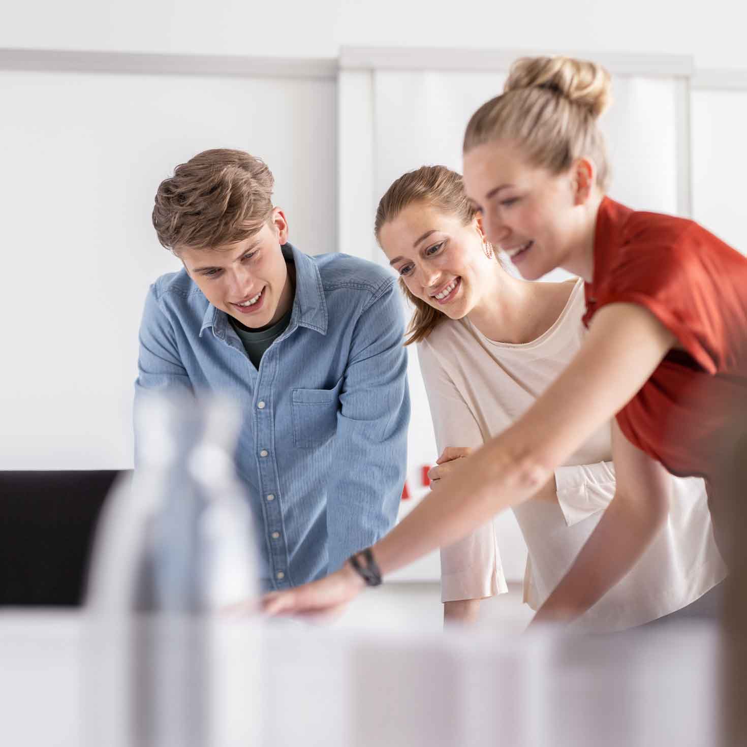 Drei junge Menschen sind über einen Tisch gebeugt