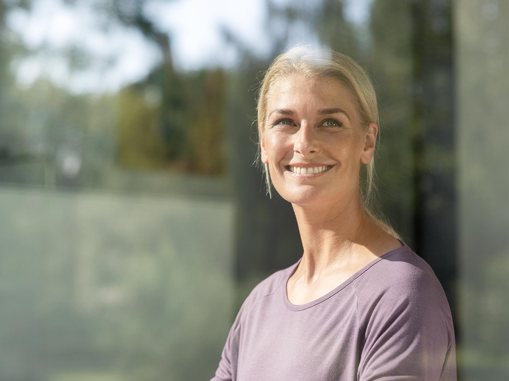 Eine Frau steht hinter einer Glasscheibe und lächelt