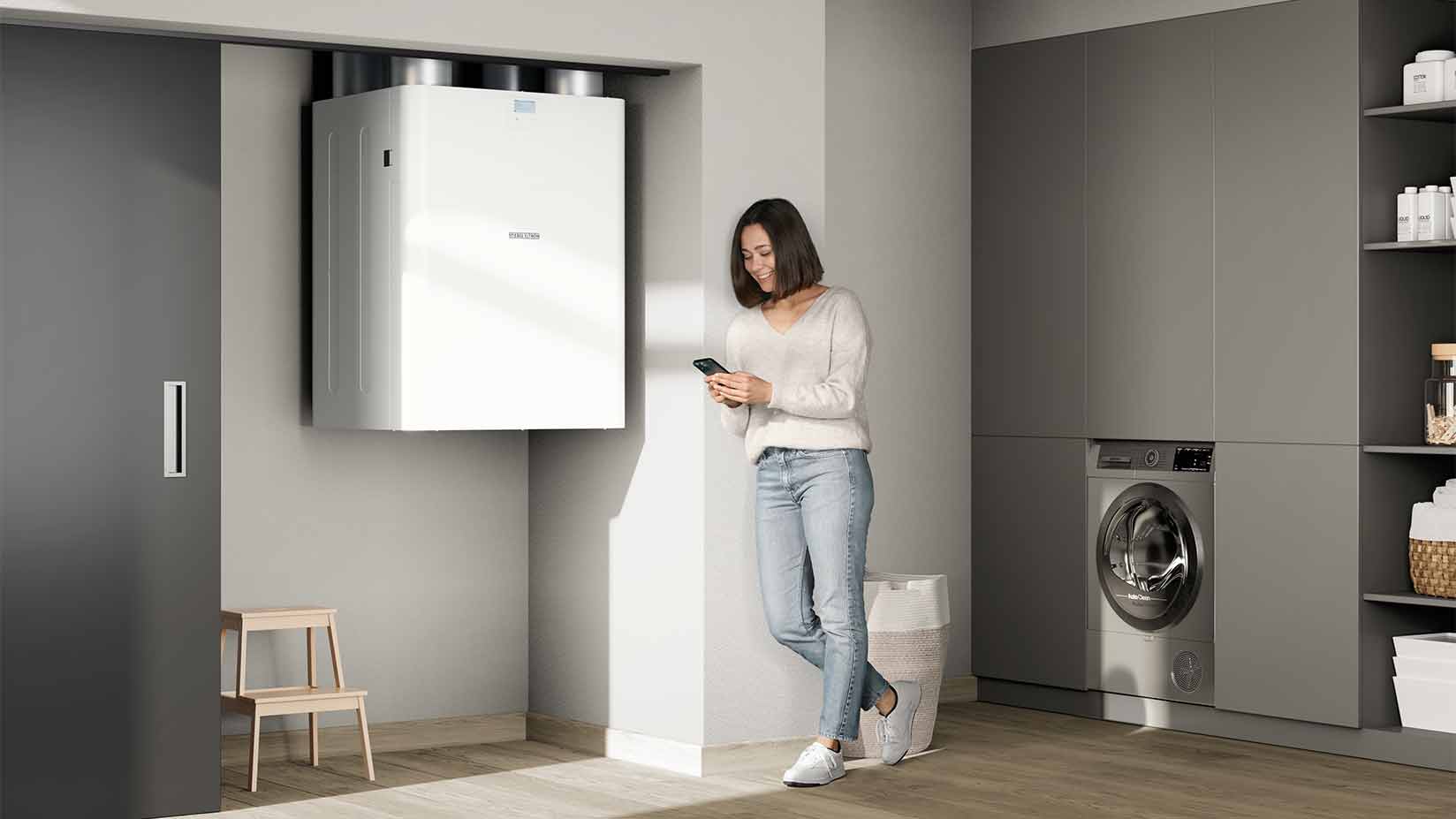 Eine Frau mit einem Handy steht an einer zentralen Lüftungsanlage