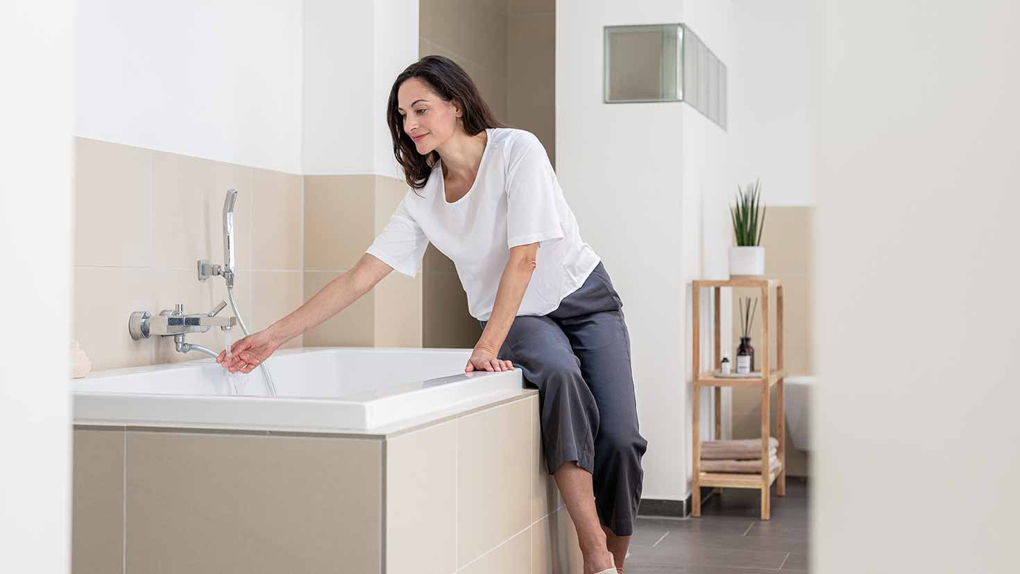 Eine lächelnde Frau lehnt über einer Badewanne