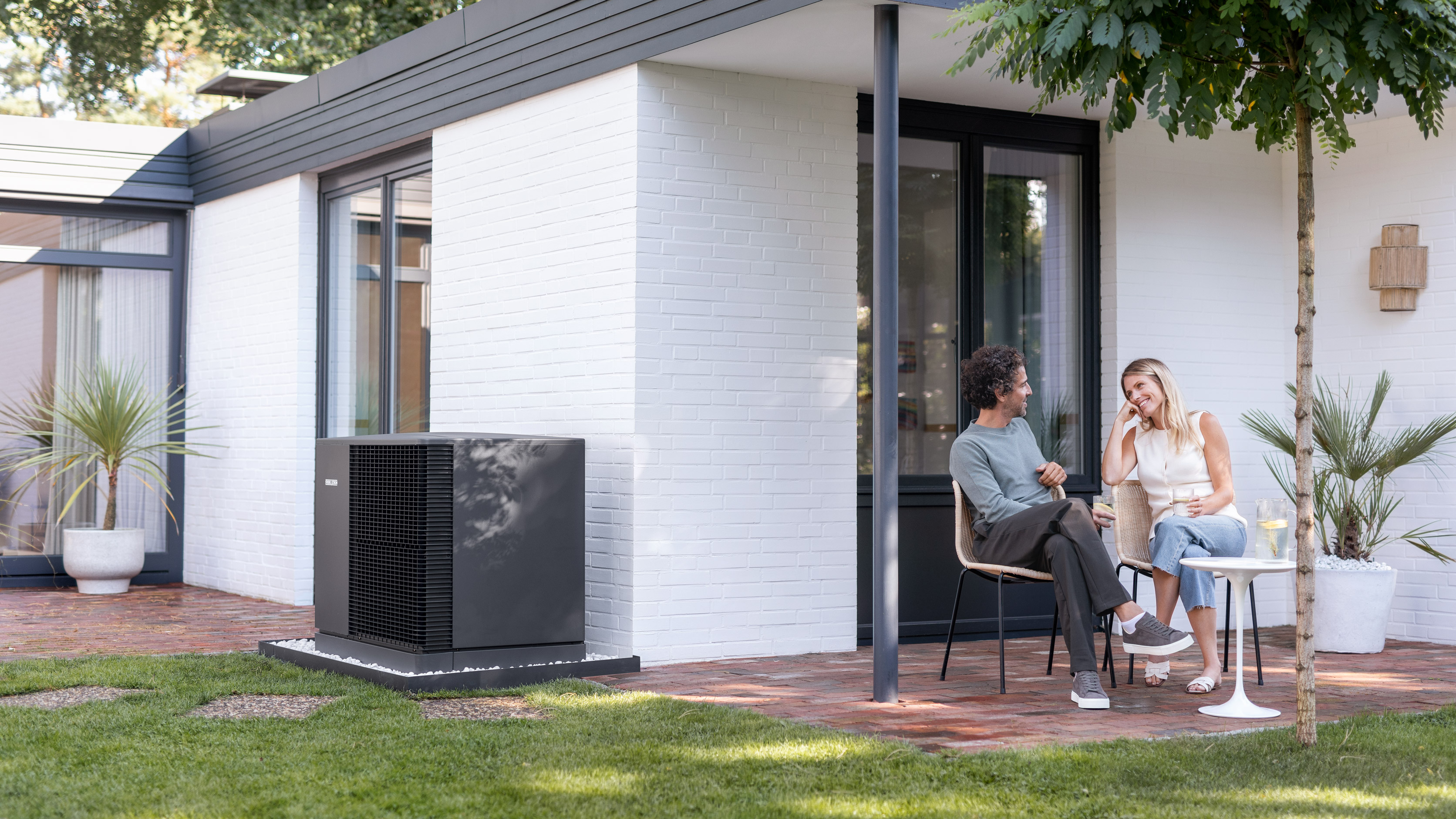 Paar sitzt auf der Terasse, daneben steht eine STIEBEL ELTRON-Wärmepumpe