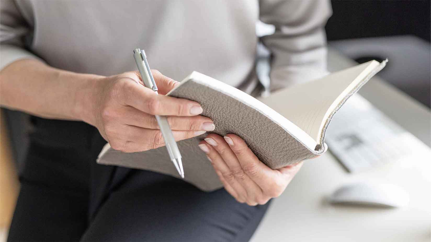 Ein Notizbuch wird in der Hand gehalten