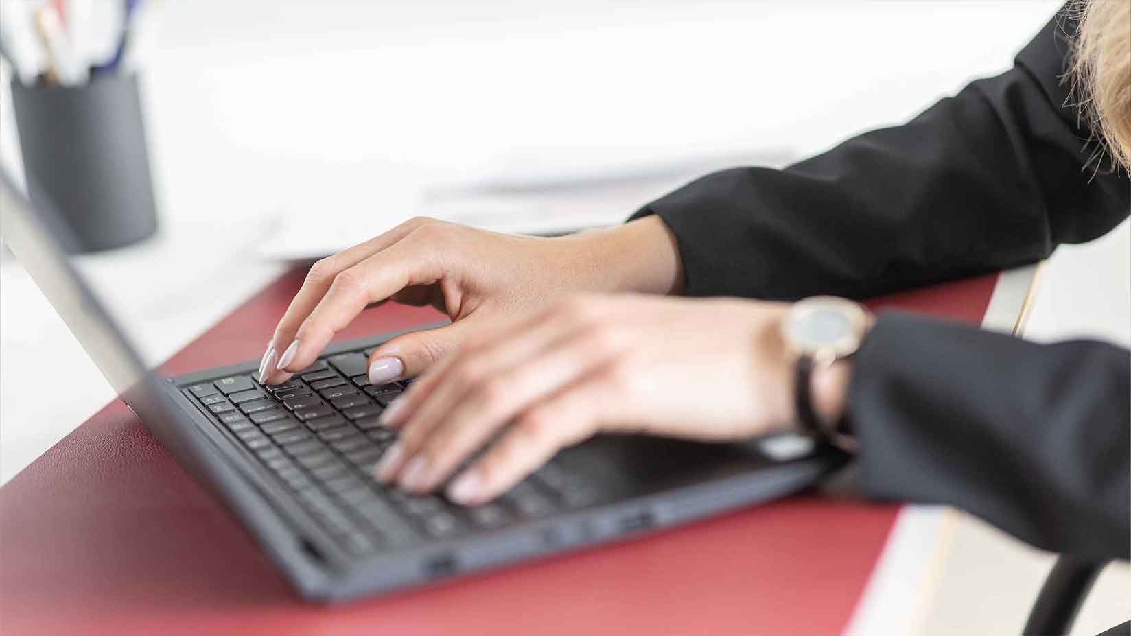 Hände schreiben auf der Tastatur eines Laptops