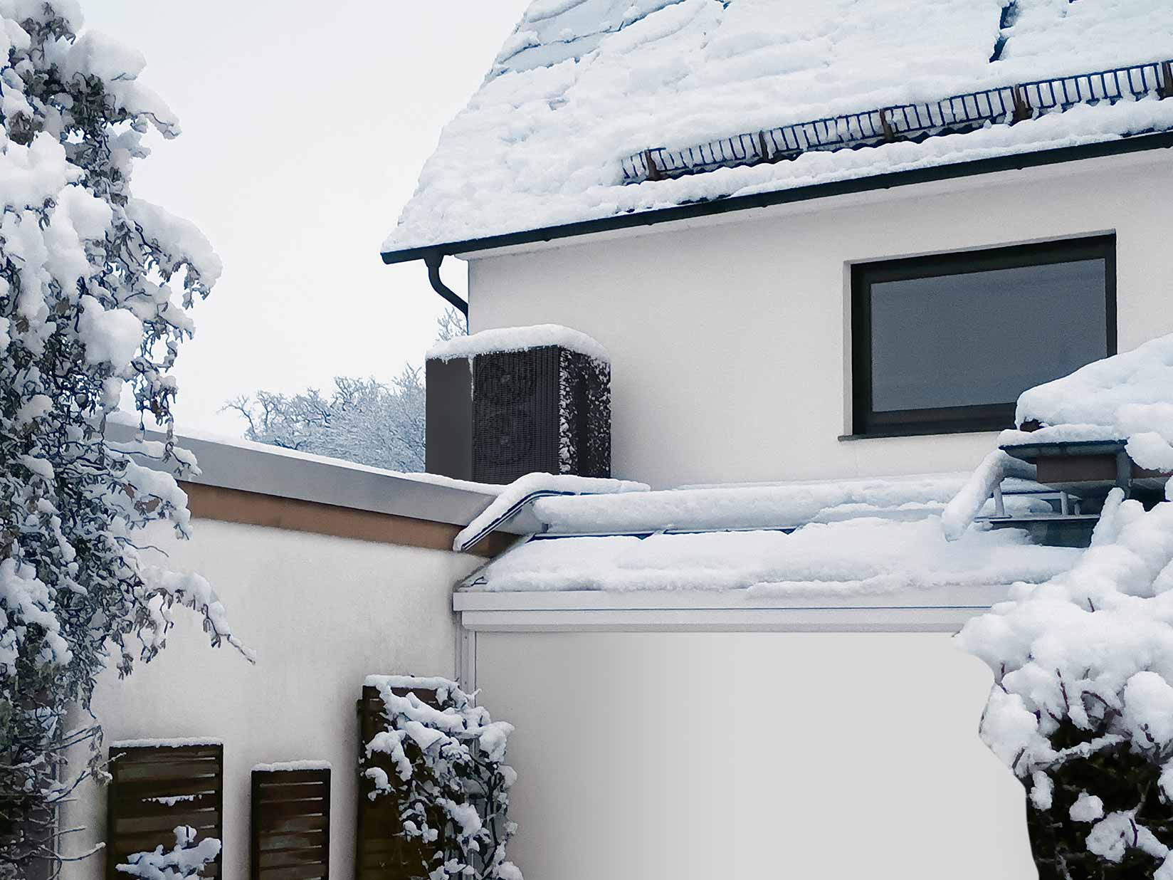 Wärmepumpe im Schnee auf einem Garagendach