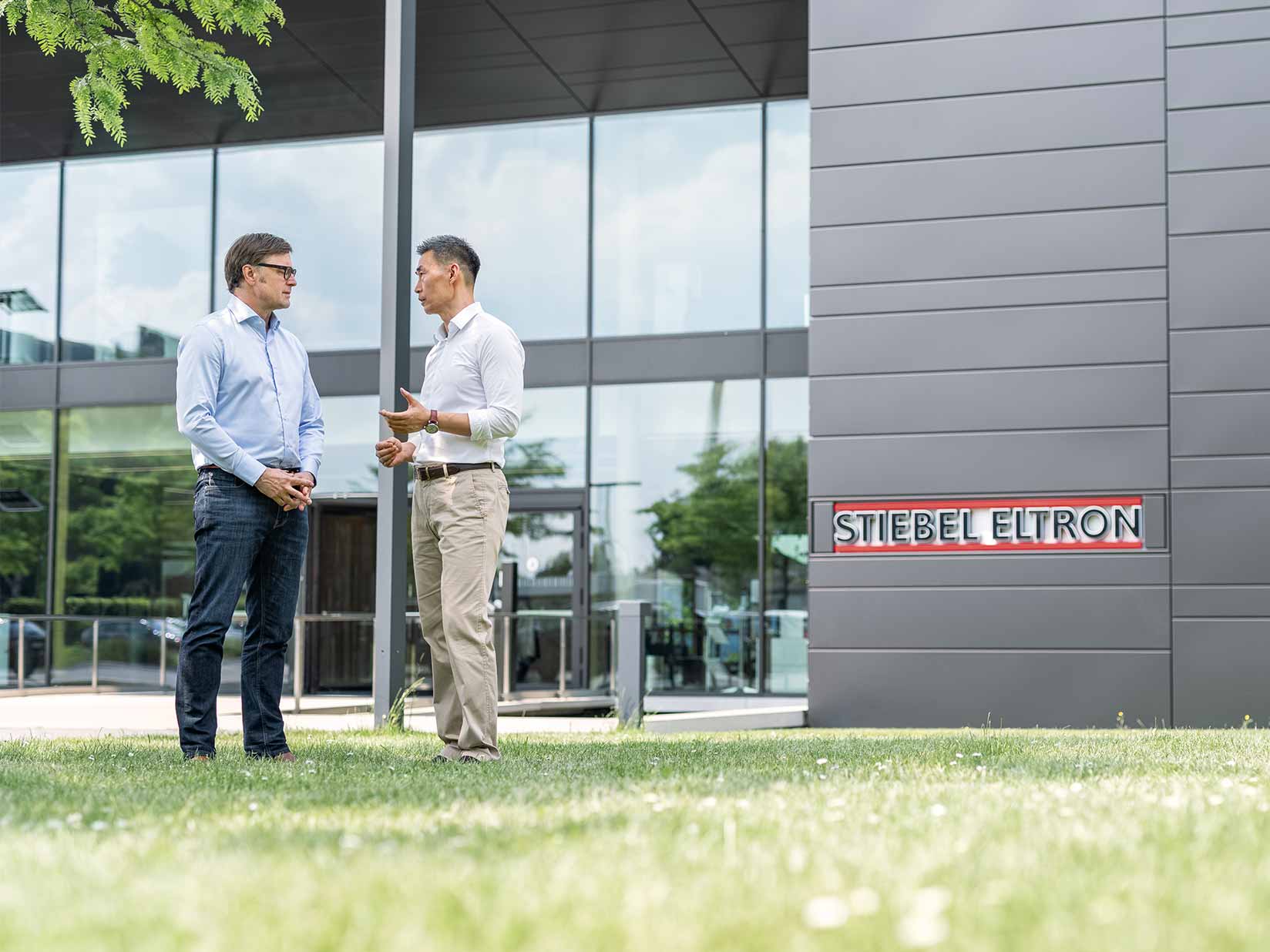 Zwei Männer im Gesrpäch vor einem modernen Gebäude
