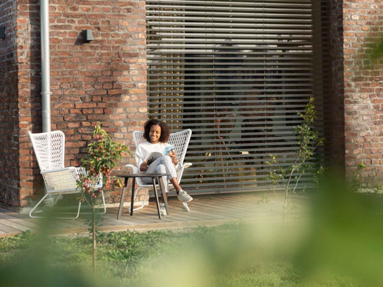 Eine Frau sitzt in einem Gartensessel und liest eine Zeitschrift
