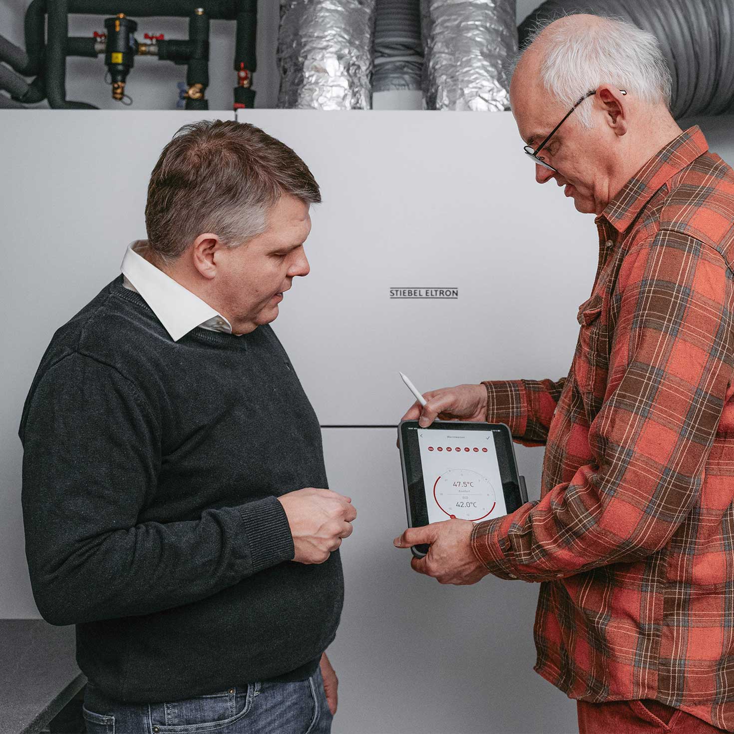 Zwei Männer bedienen ein Lüftungsintegralgeräts von STIEBEL ELTRON an einem Tablet