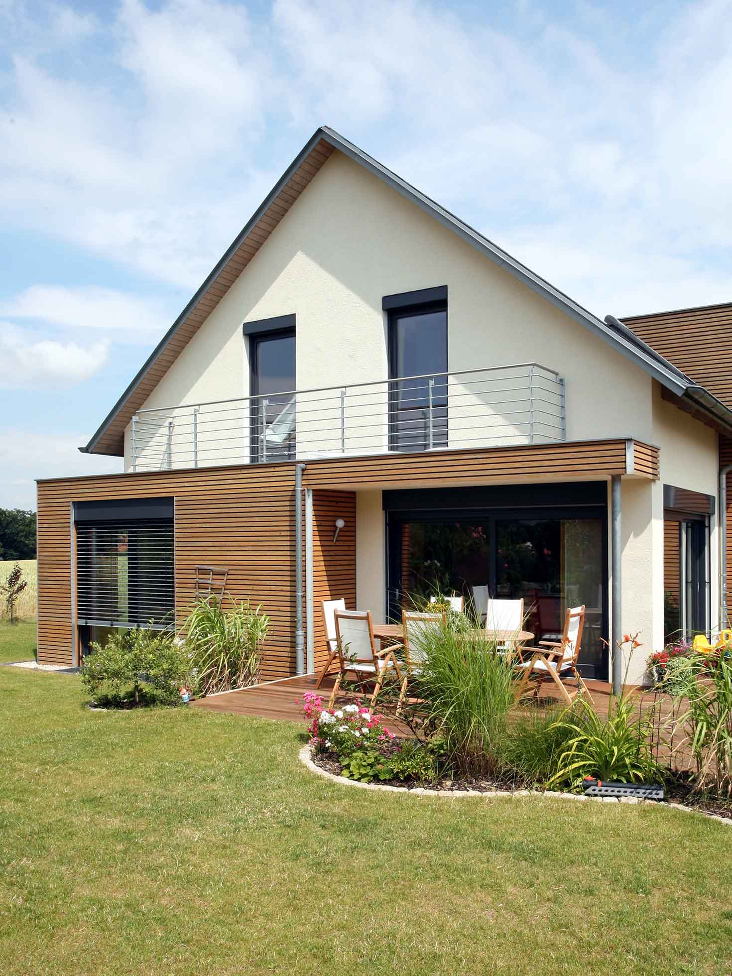 Ein modernes Einfamilienhaus mit Terasse und Balkon und einer gepflegten Rasenfläche im Vordergrund.