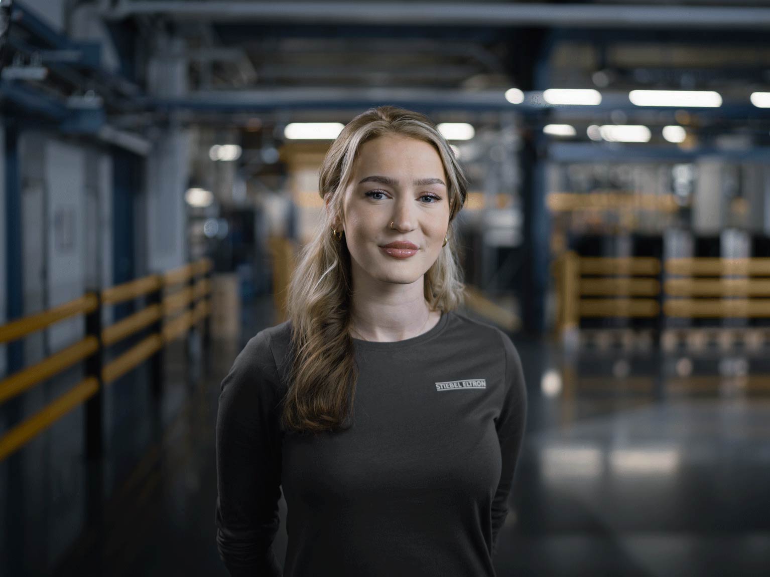 Ein STIEBEL ELTRON Mitarbeiterin steht in einer modernene Produktionshalle für Wärmepumpe.