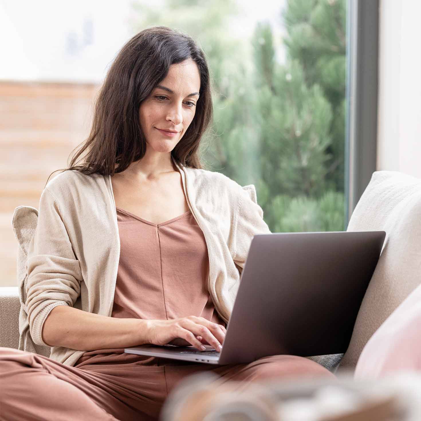 Frau sitzt mit Laptop auf dem Sofa