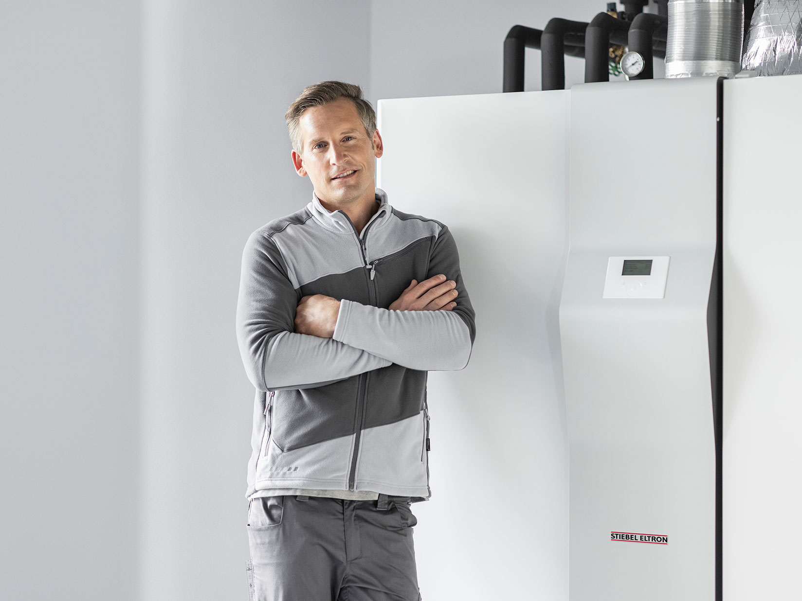 Handwerker steht vor Wärmepumpe