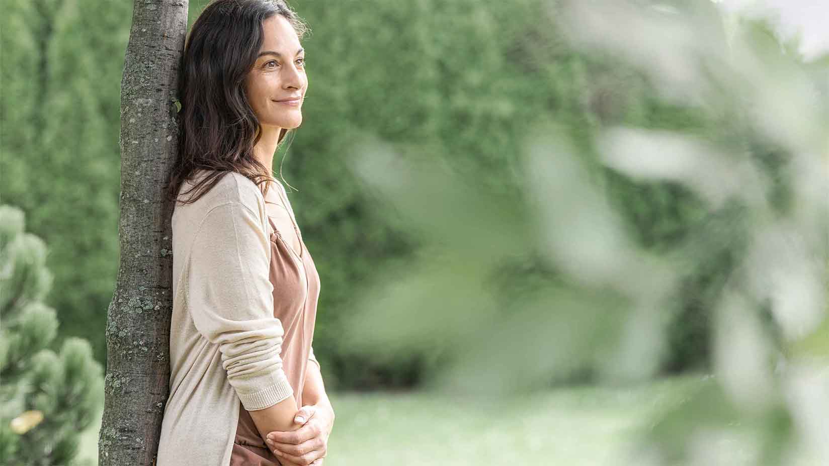 Frau lehnt sich an einen Baum