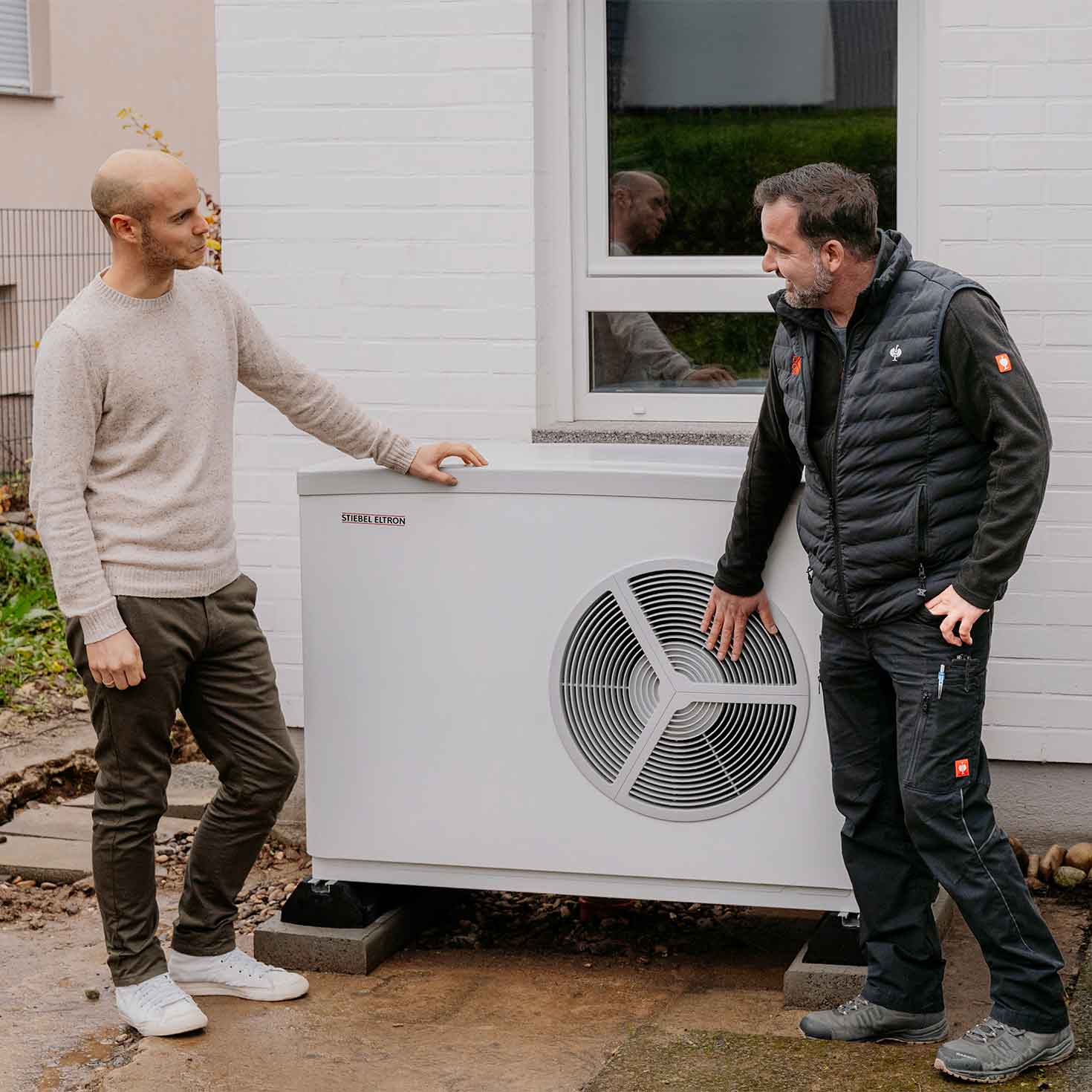 Zwei Männer stehen neben einer STIEBEL ELTRON-Wärmepumpe und unterhalten sich